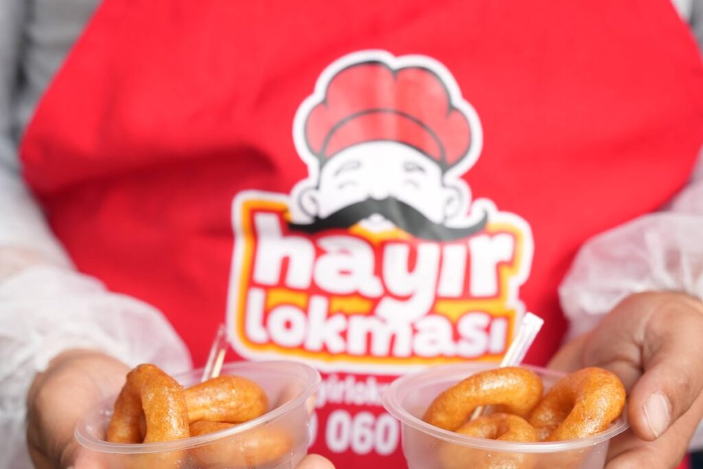 Hayır Lokmasının Anlamı ve Hikayesi 2 Hayır Lokması önlüklü görevli iki kâse sıcak lokma ikram ediyor